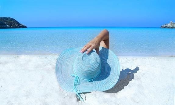 zdjęcie poglądowe, kobieta w kapeluszu lezy na plaży