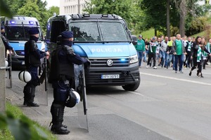 radiowozy policyjne jadące ulicą i policjanci zabezpieczający przemarsz osób