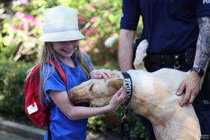 dziewczynka obejmuje głowę psa, którego trzyma policjant