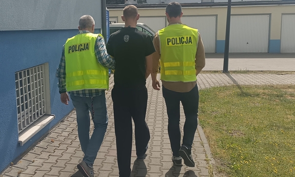 dwóch policjantów prowadzi zatrzymanego mężczyznę