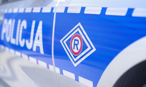 logo ruchu drogowego i napis policja na drzwiach radiowozu policyjnegp