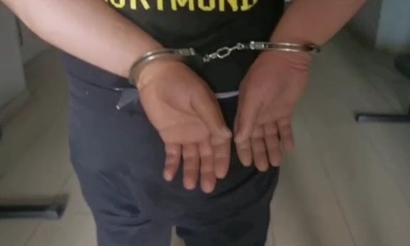 zatrzymany w kajdankach na rękach, które trzyma z tyłu