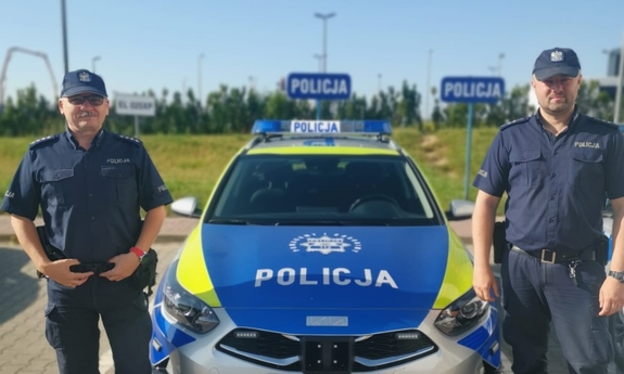 dwaj policjanci stoją przed radiowozem policyjnym