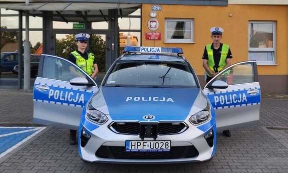 policjanci ruchu drogowego przy radiowozie i przed Komendą Powiatowa Policji w Wieruszowie