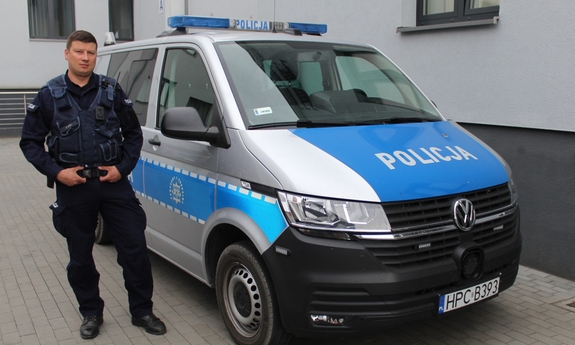 policjant stoi przy radiowozie policyjnym