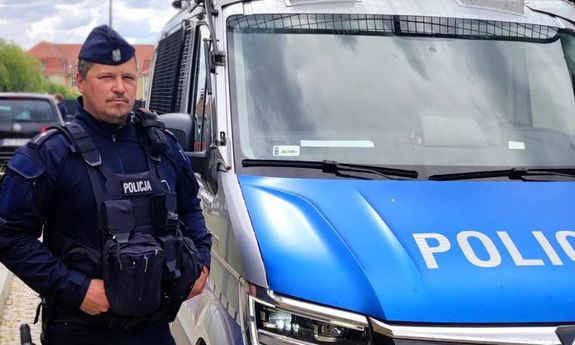 umundurowany policjant stoi przy radiowozie