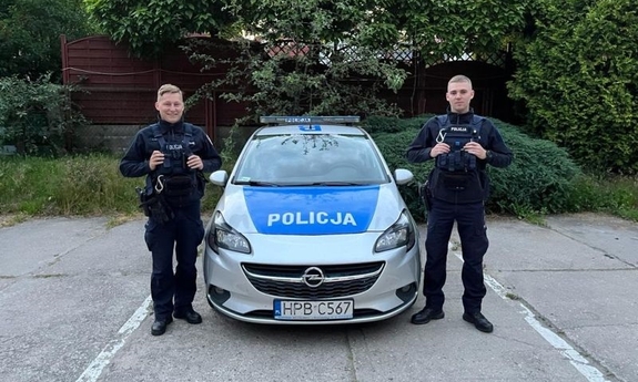 umundurowani policjanci stoją przy radiowozie