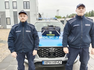 umundurowani policjanci stoją przy radiowozie