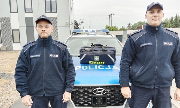 umundurowani policjanci stoją przy radiowozie