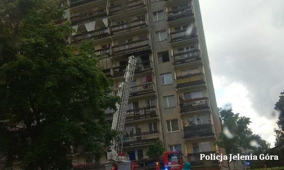 Wóz strażacki z drabiną sięgający do okna jednego z pomieszczeń w bloku mieszkalnym