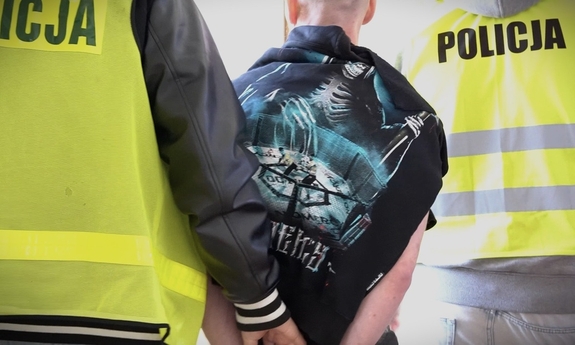 dwóch policjantów prowadzi zatrzymanego mężczyznę