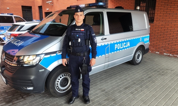 umundurowany policjant stoi przy radiowozie