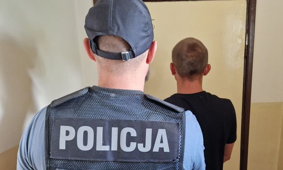 policjant prowadzi zatrzymanego - widok z tyłu