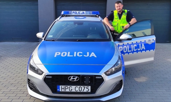 umundurowany policjant stoi przy radiowozie