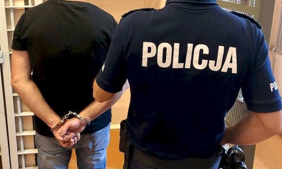 policjant z zatrzymanym zakutym w kajdanki