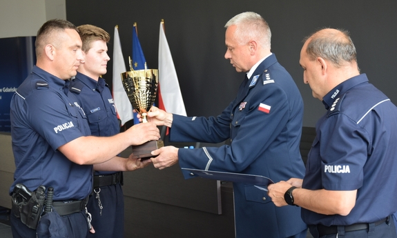 insp. Bogusław Ziemba I Zastępca Komendanta Wojewódzkiego Policji w Gdańsku oraz nadkom. Jacek Domagała Naczelnik Wydziału Prewencji KWP w Gdańsku wręczają zwycięskiej parze patrolowej pamiątkowy puchar