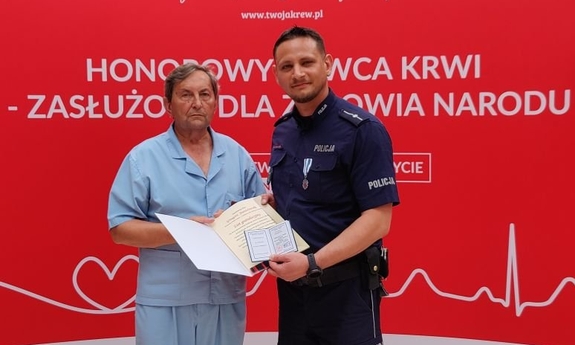 odznaczony policjant z mężczyzną, trzyma dyplom i legitymację