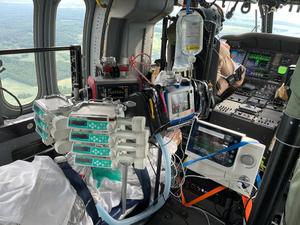 wnętrze lecącego śmigłowca, aparatura medyczna do monitorowania stanu pacjenta, przez okna widać teren, nad którym leci śmigłowiec