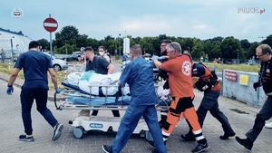 Pacjent jest transportowany na specjalnym łóżku na kółkach przez personel szpitalny i ratowników ze śmigłowca do szpitala