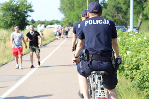 dwaj policjanci jadący rowerami ścieżką dla rowerów - widok z tyłu