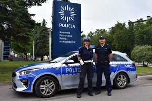 umundurowani policjant i policjantka stoją przy radiowozie