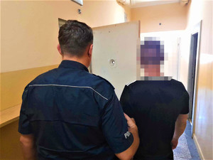 policjat z zatrzymanym mężczyną na korytażu