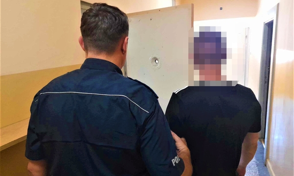 policjat z zatrzymanym mężczyną na korytażu