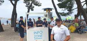 dwaj polscy policjanci wspólnie z chorwackimi policjantami stoją przy punkcie informacyjnym przy plaży