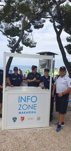 polski policjant wspólnie z chorwackimi policjantami stoją przy punkcie informacyjnym przy plaży