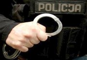 ręka z kajdankami, w tle napis policja na mundurze