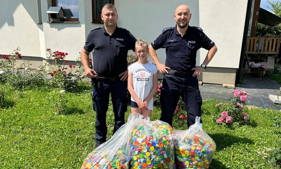 Policjanci wraz z Aleksandrą Wojnar i przekazane trzy duże worki wypełnione nakrętkami