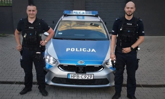 Dwaj policjanci stojący przy radiowozie