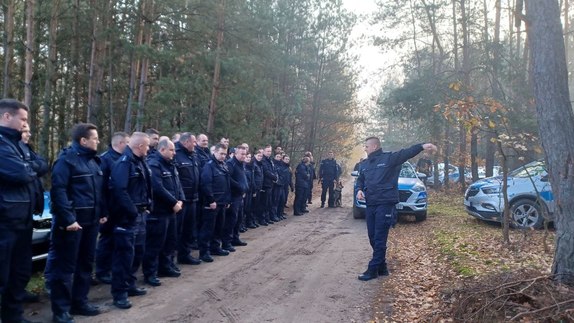 pluton policjantów w lesie stoi przed swoim dowódcą przed rozpoczęciem poszukiwań