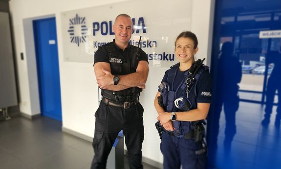 umundurowana policjantka i strażnik miejski stoją na korytarzu budynku Komendy Miejskiej Policji w Białymstoku