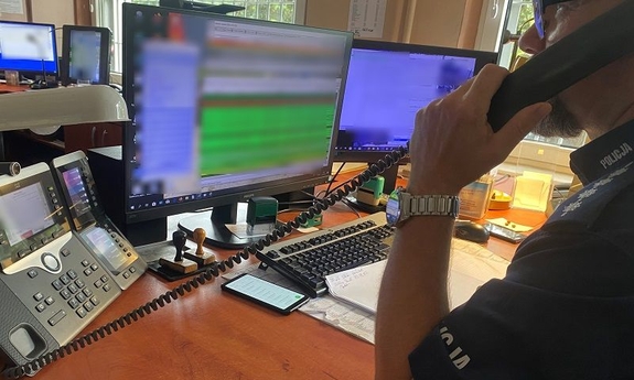 policjant siedzi przy biurku i rozmawia przez służbowy telefon