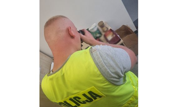 policjant w żółtej kamizelce fotografuje zabezpieczone skradzione przedmioty