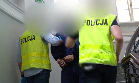 dwaj policjanci prowadzą po schodach do góry zatrzymanego mężczyznę