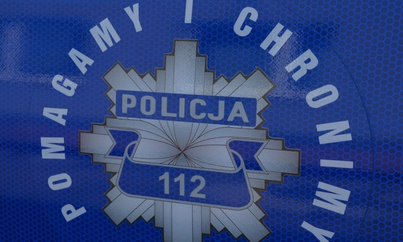 Policyjna gwiazda z napisem pomagamy i chronimy na drzwiach radiowozu policyjnego