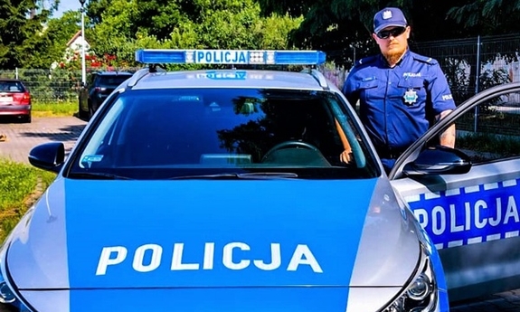 umundurowany policjant stoi przy radiowozie