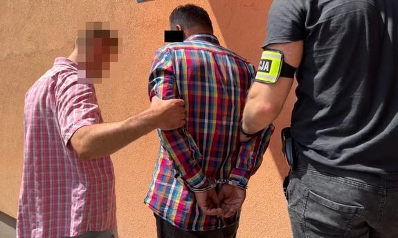 dwaj policjanci ubrani po cywilnemu prowadzą zatrzymanego mężczyznę
