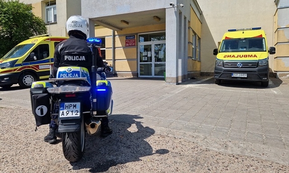 motocykl policyjny i karetka pogotowia przed budynkiem szpitala
