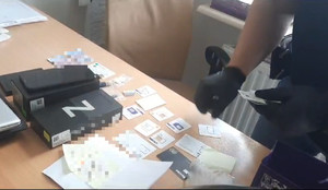 widoczna dłoń policjanta oraz teczki i karty sim rozłożone na stole