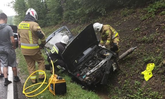 strażacy pracują przy rozbitym aucie, które wpadło do rowu