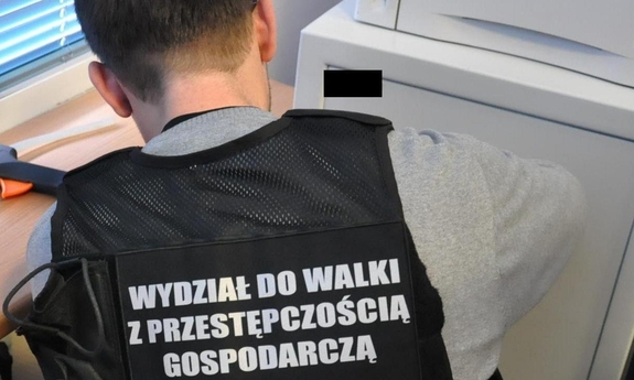 policjant w kamizelce z napisem Przestępczość gospodarcza w trakcie otwierania metalowej szafy