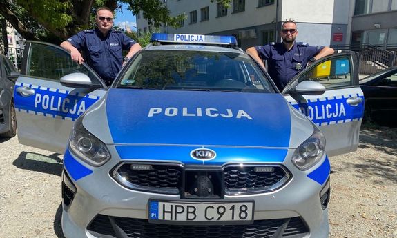 Policjanci w mundurze stojący przy radiowozie w tle komisariat policji Wrocław Stare -Miasto