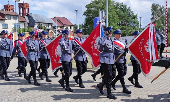 grupa policjantów maszerująca ze sztandarami