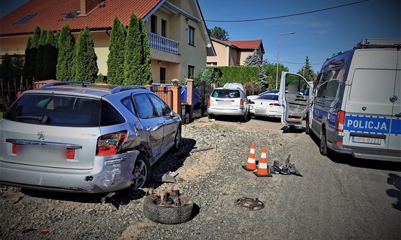 Radiowóz stojący koło samochodu osobowego z zerwanym tylnym kołem