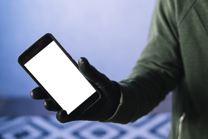 Ręka mężczyzny, który w dłoni ubranej w rękawiczkę trzyma smartfon z pustym ekranem