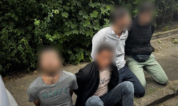 cztery osoby siedzące na chodniku
