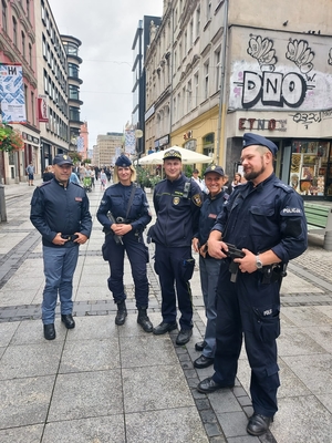Czwórka umundurowanych policjantów, dwójka polskich policjantów, dwójka włoskich policjantów oraz strażnik miejski w ubiorze służbowym stoi na ulicy